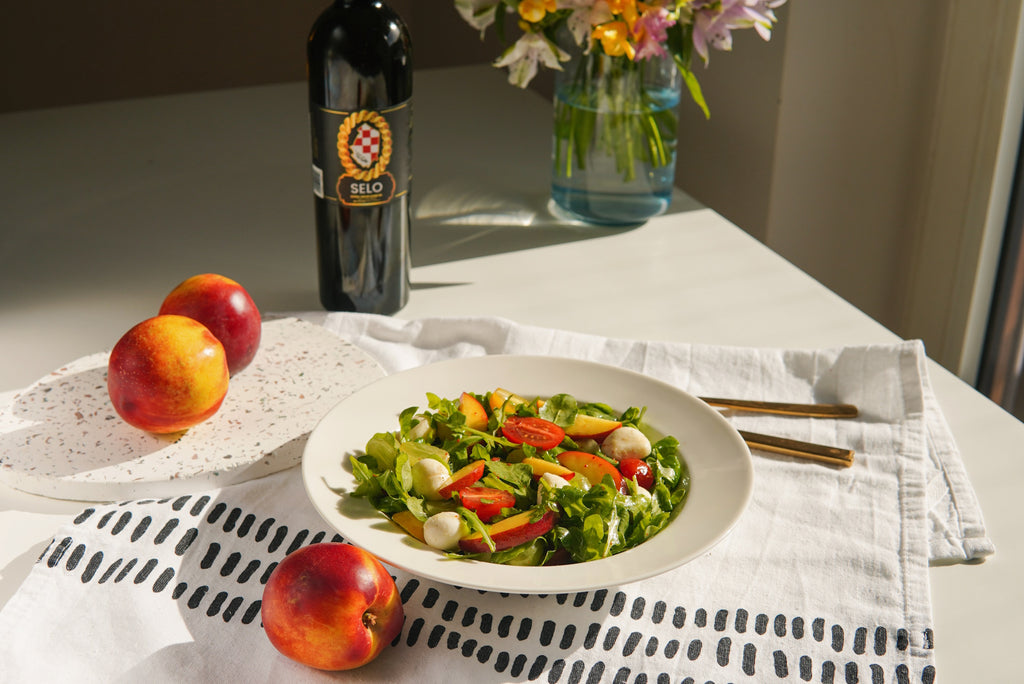 A fresh Arugula Nectarine Summer Salad, topped with a light and zesty dressing made from Croatian olive oil, for a delightful and refreshing meal.
