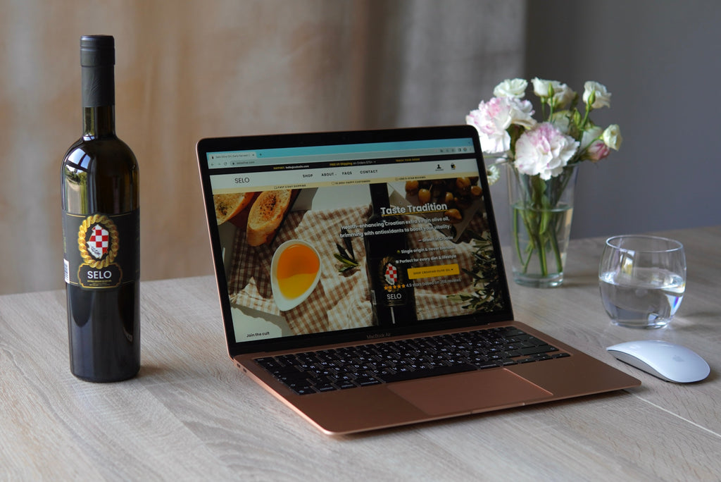 Bottle of olive oil positioned beside a laptop emitting blue light, illustrating olive oil's protective properties against digital screen exposure.
