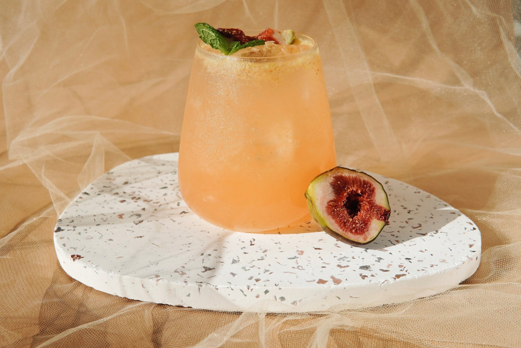 A refreshing cocktail made with fresh figs, vodka, and a splash of citrus, garnished with a fig slice and mint sprig.