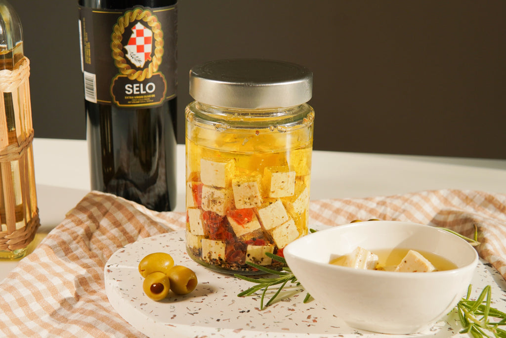 Jar of creamy white feta cheese cubes, brined and preserved in shimmering olive oil.