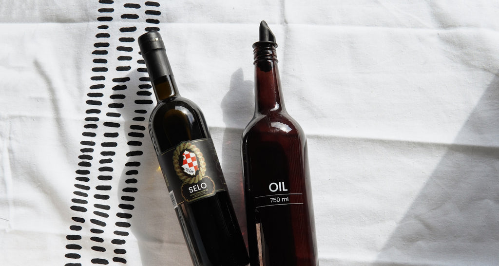 Two bottles side by side, one 'Extra Virgin Olive Oil', the other 'Virgin Olive Oil', illustrating the visual differences between the two types of olive oil.