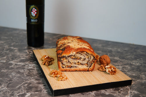 Walnut Roll (Orahnjača) showcasing its swirls and rich walnut filling, complemented by Croatian olive oil, on a rustic table.