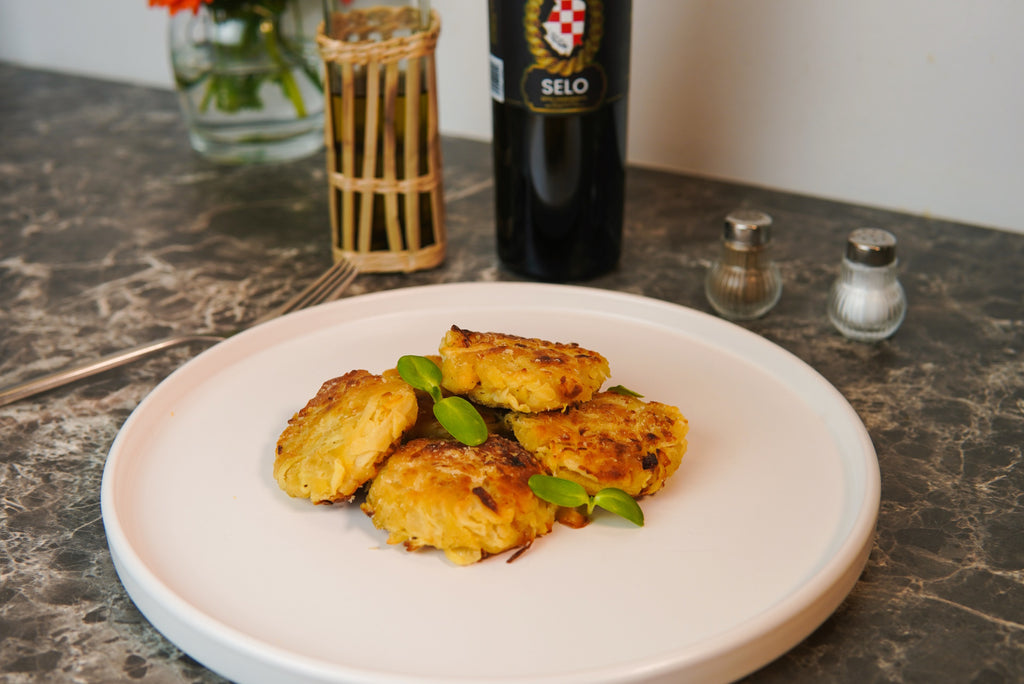 Golden and crispy Cabbage Cutlets (Kotleti od Kupusa) cooked in Croatian olive oil, arranged on a plate with a side of fresh shredded cabbage, offering a unique and delicious vegetarian meal.